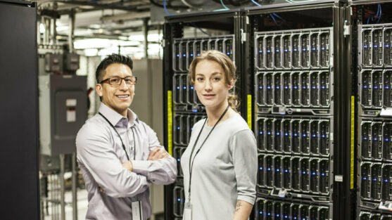 Caucasian man and woman technicians in a large computer server farm.